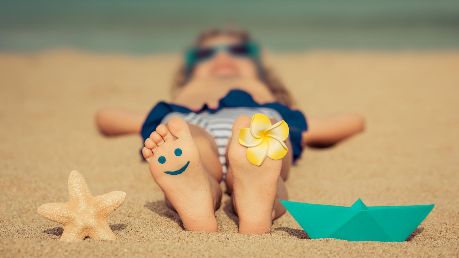 Dětská bosá chodidla v písku symbolizující přirozený pohyb a barefoot chůzi