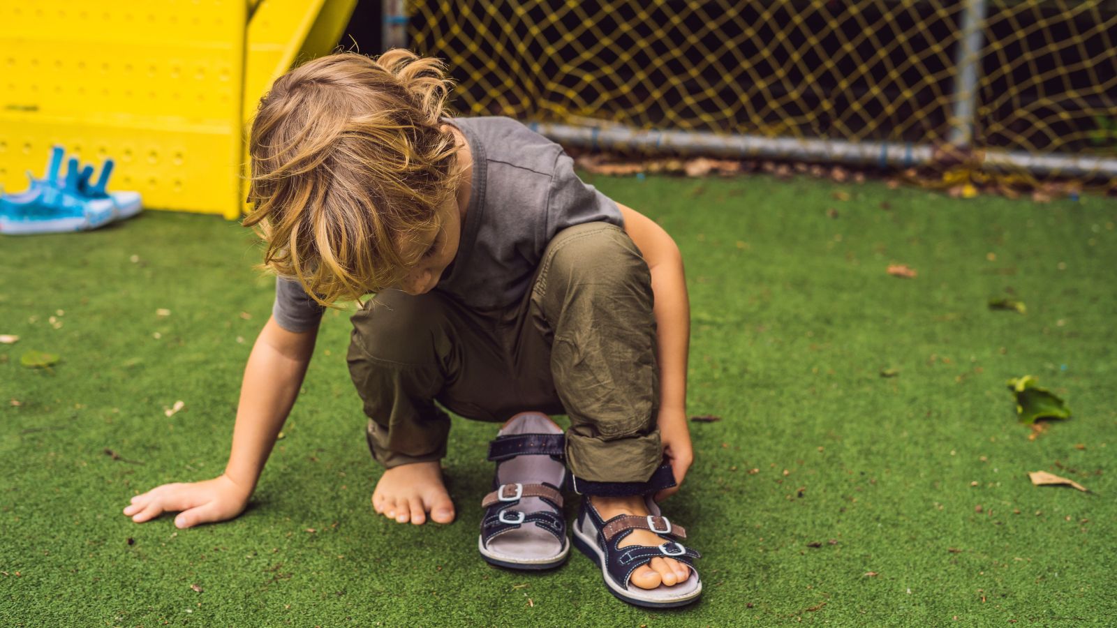 Dítě si obouvá dětské sandály na letní hraní venku