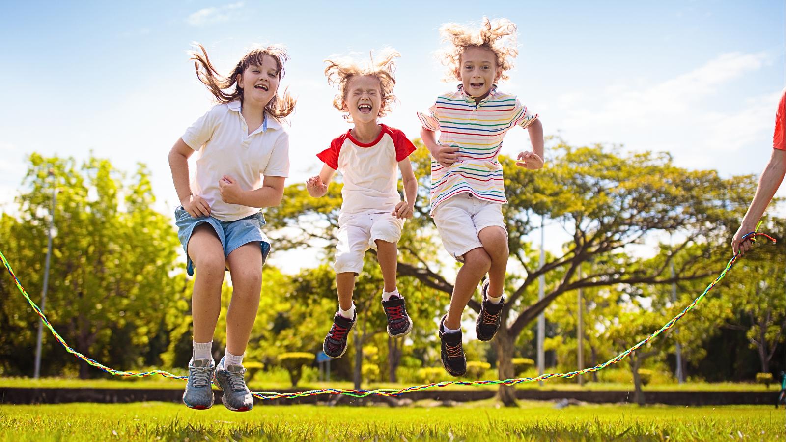 Děti skákající přes švihadlo v dětských teniskách při venkovní hře