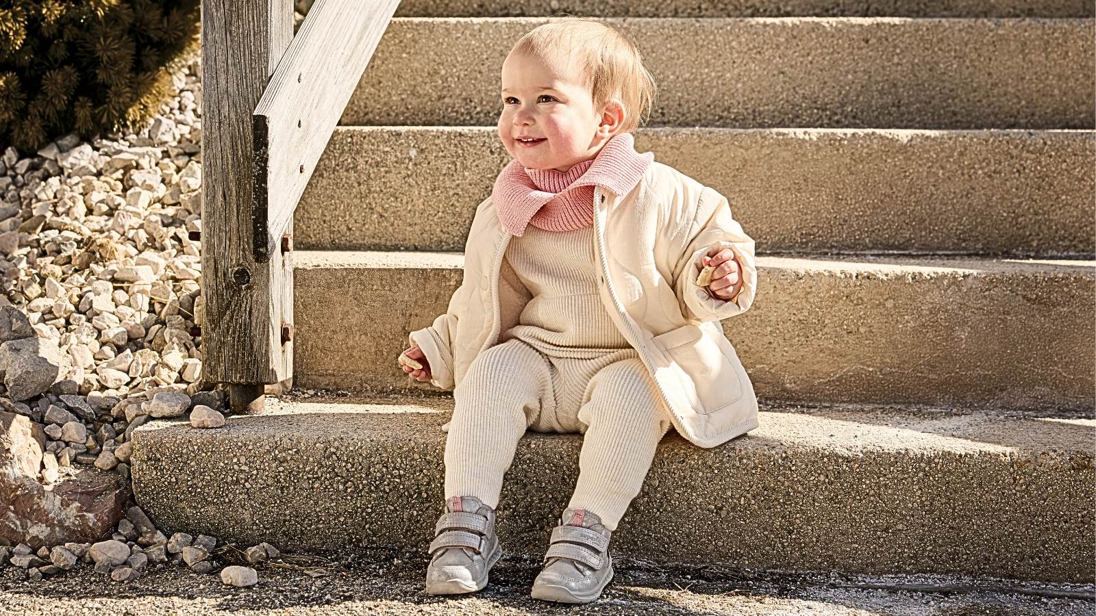 Batole v prvních dětských botách sedí na schodech venku